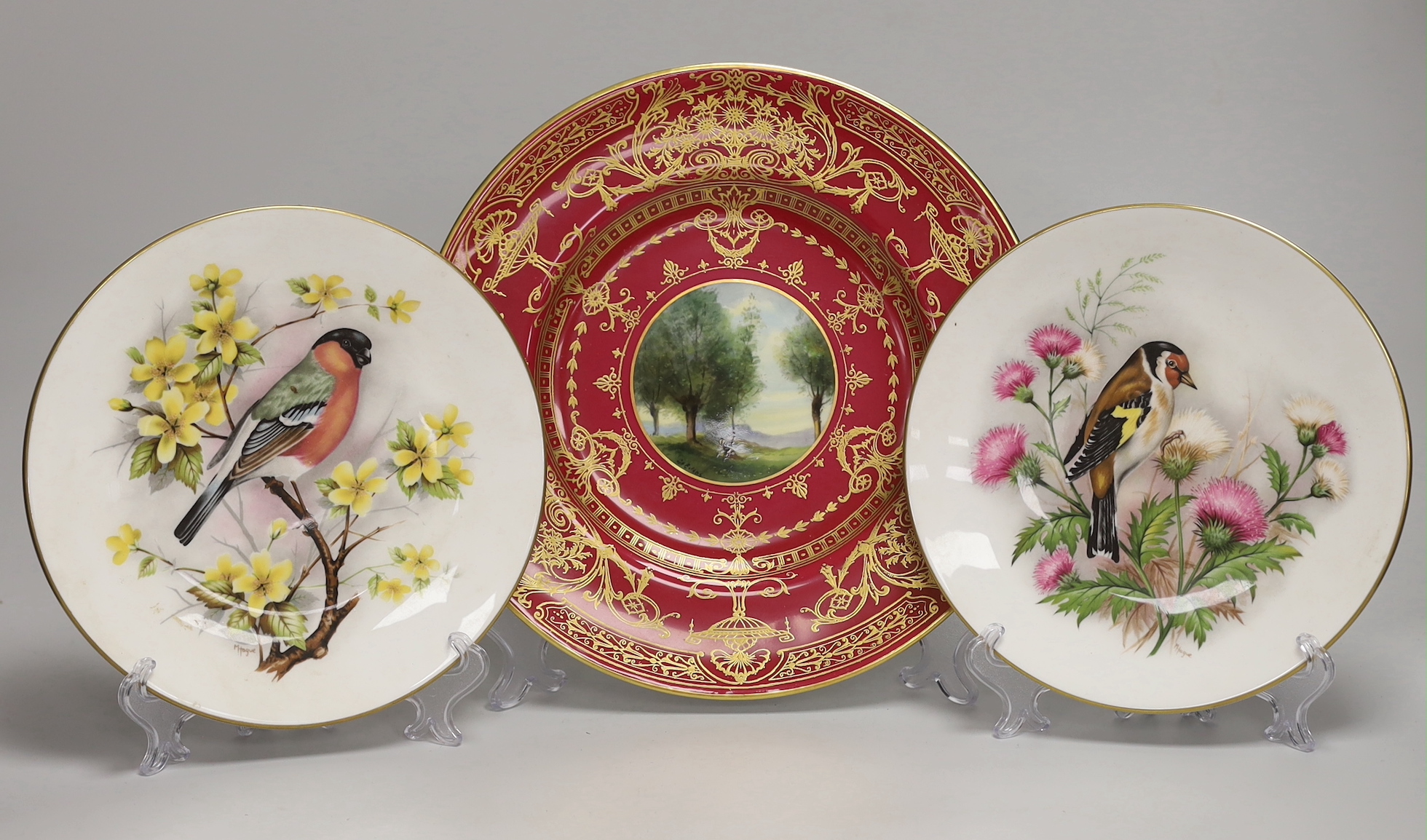 A Royal Worcester fine plate painted with a figure in a tree line landscape by G. Evans, signed and Royal Worcester plates by M Tague, signed with a Bullfinch and a Gold Finch                                             