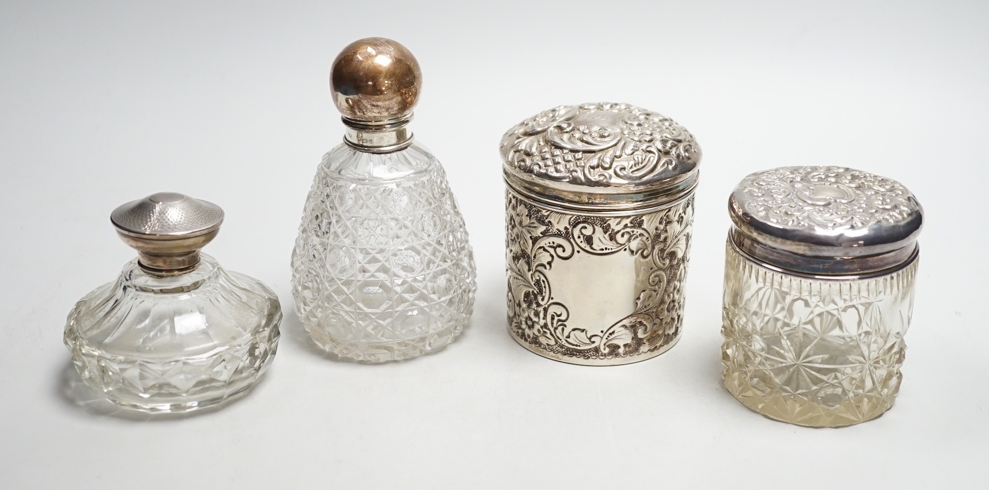 Two repousse silver lidded toilet jars, including glass, largest, 95mm and two silver mounted glass scent bottles.                                                                                                          