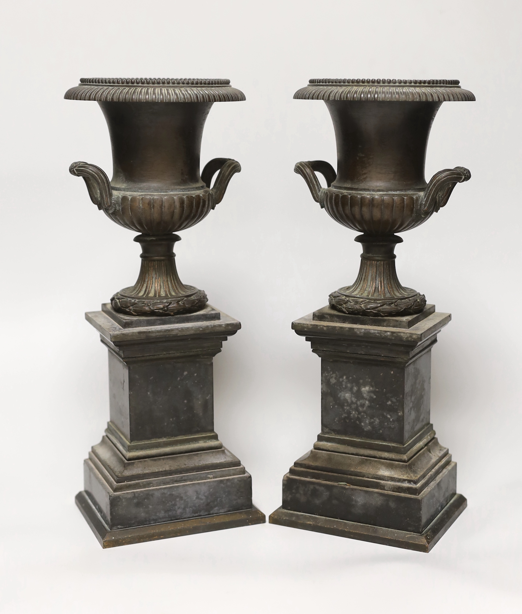 A pair of late 19th century bronze campana urns on rectangular pedestals, each 32cm high                                                                                                                                    