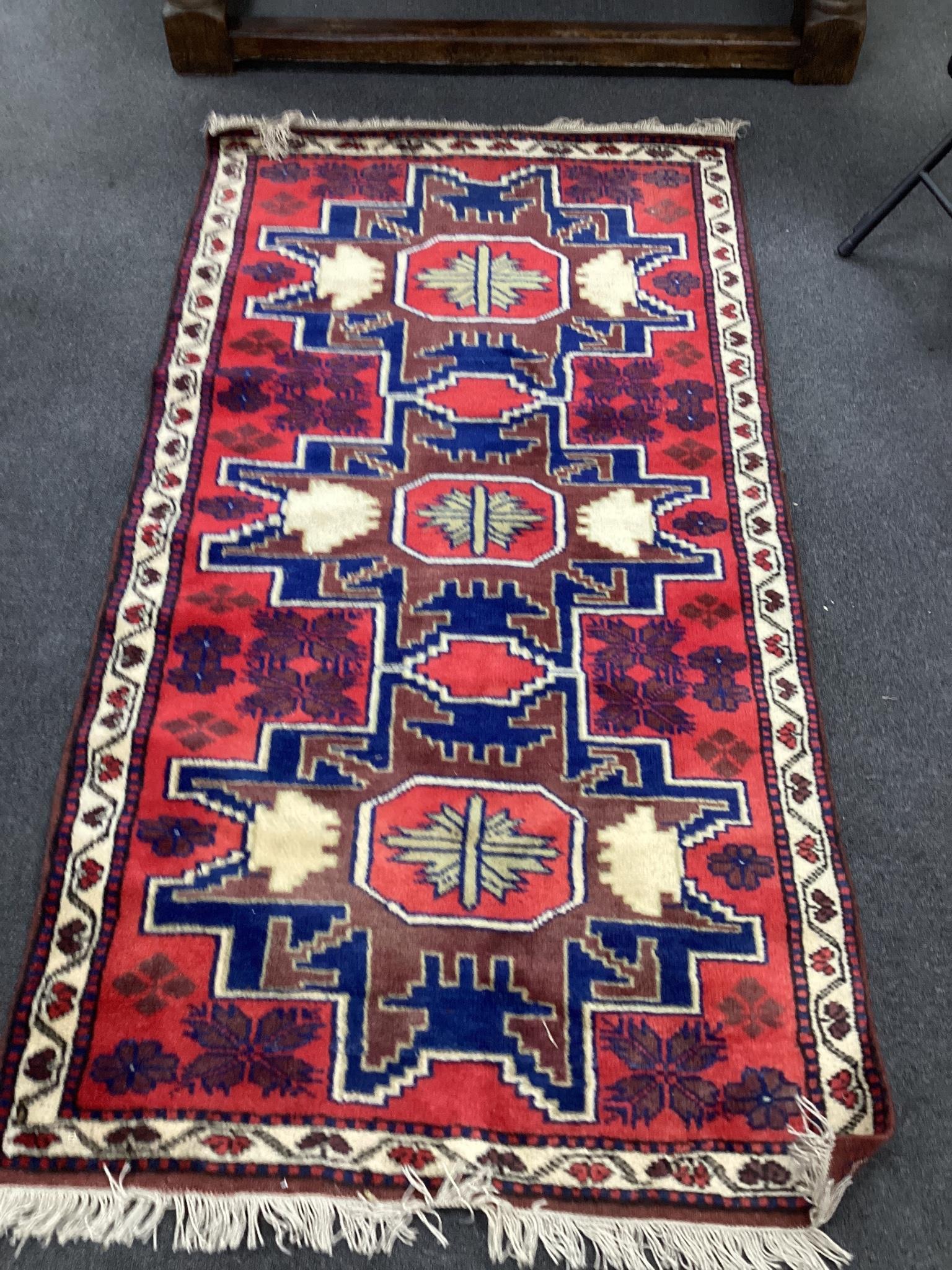 A Caucasian style red ground triple medallion rug, 180 x 98cm                                                                                                                                                               