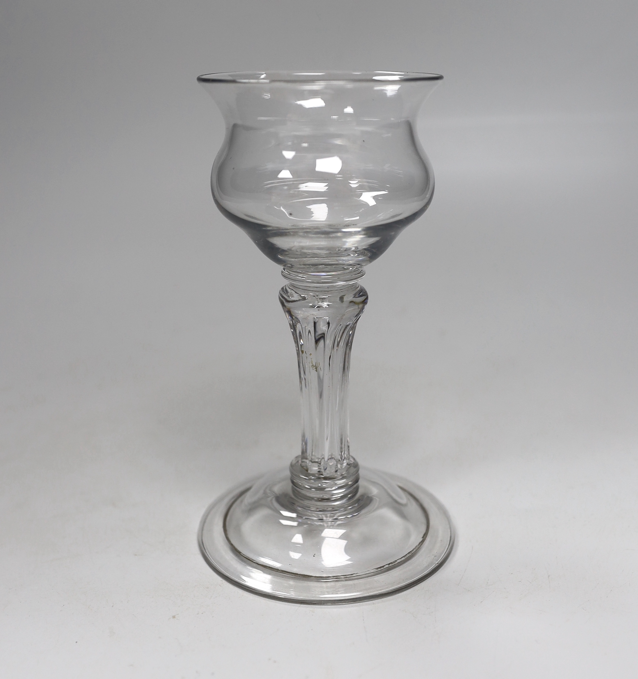 An English lead crystal champagne or sweetmeat glass c.1740, with double ogee bowl, with collar under the bowl, over a twelve sided debased, moulded pedestal stem over two collars at the base, with domed, folded foot and