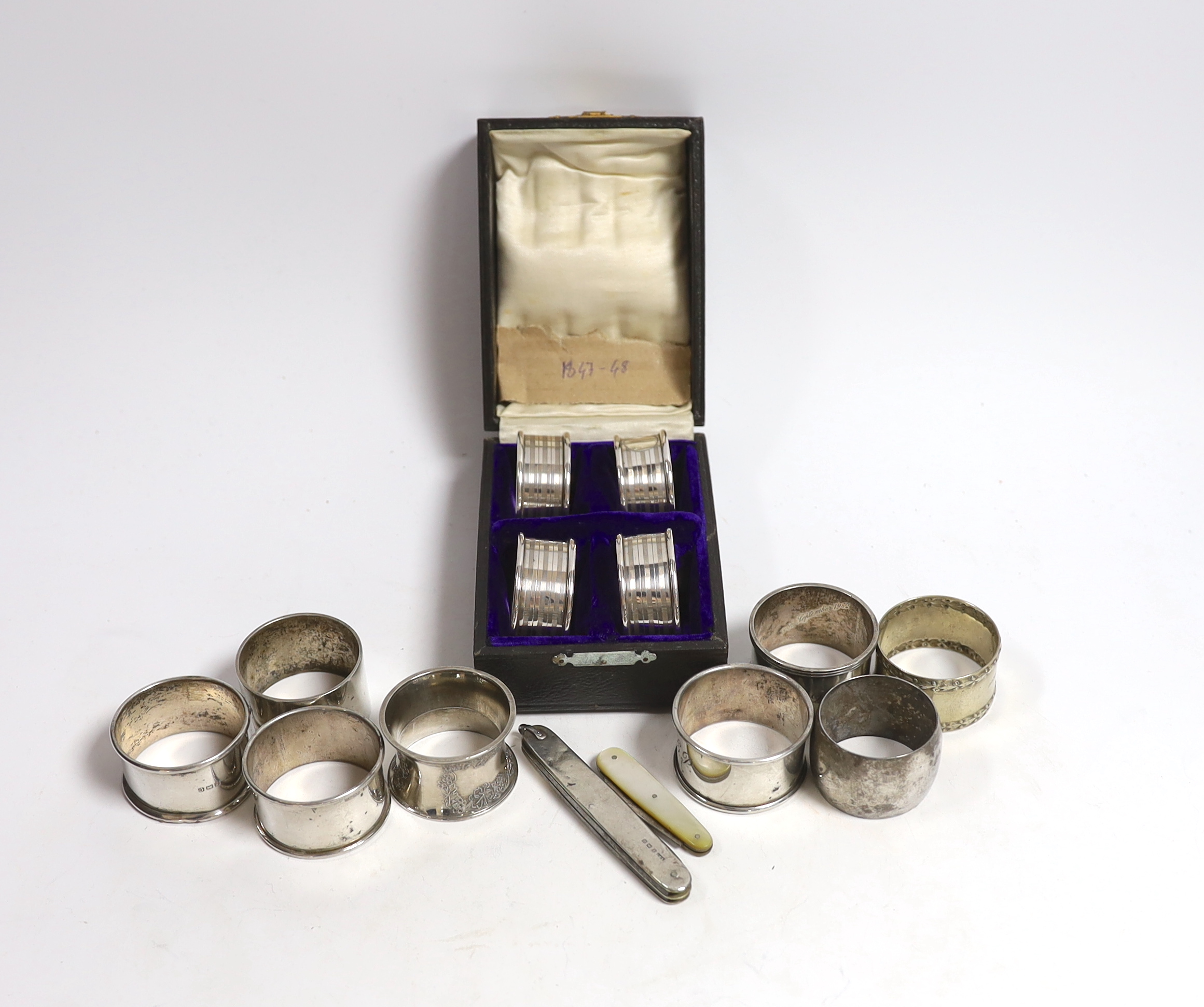 A cased set of four George V silver napkin rings, Rolason Brothers, Birmingham, 1920, together with five other assorted silver napkin rings, three plated napkin rings, two mother of pearl mounted fruit knives and a silve