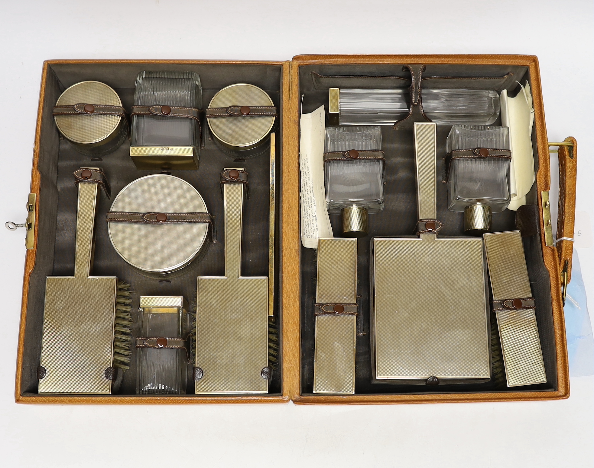 A George VI pig skin travelling vanity case, containing fourteen engine turned silver gilt mounted accoutrements, including toilet jars, mirror and brushes etc, Goldsmiths & Silversmiths Co Ltd, London, 1947/8/9, case 32