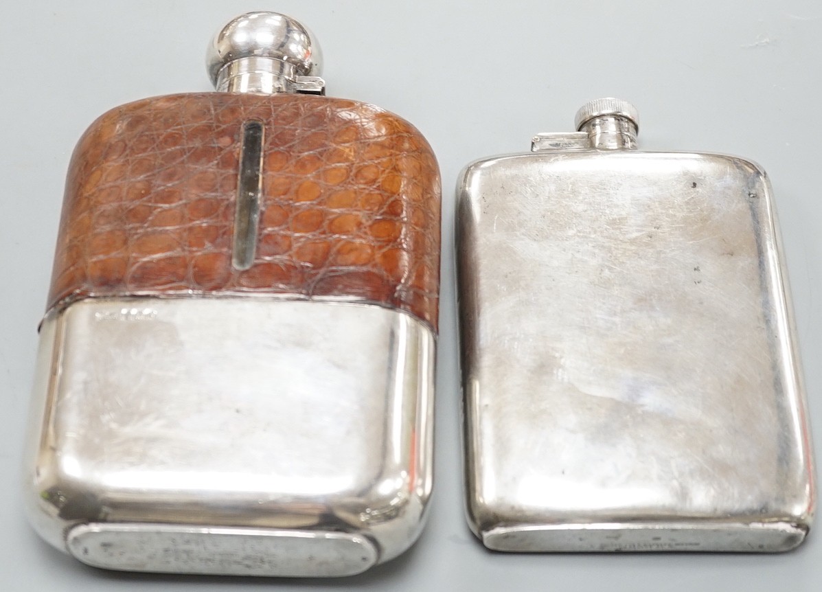 A George VI silver hip flask, Goldsmiths & Silversmiths Co Ltd, London, 1938, 15.4cm, 7.6oz and a large George V silver and crocodile skin mounted glass hip flask, James Dixon & Sons, Sheffield, 1920, 19cm.              
