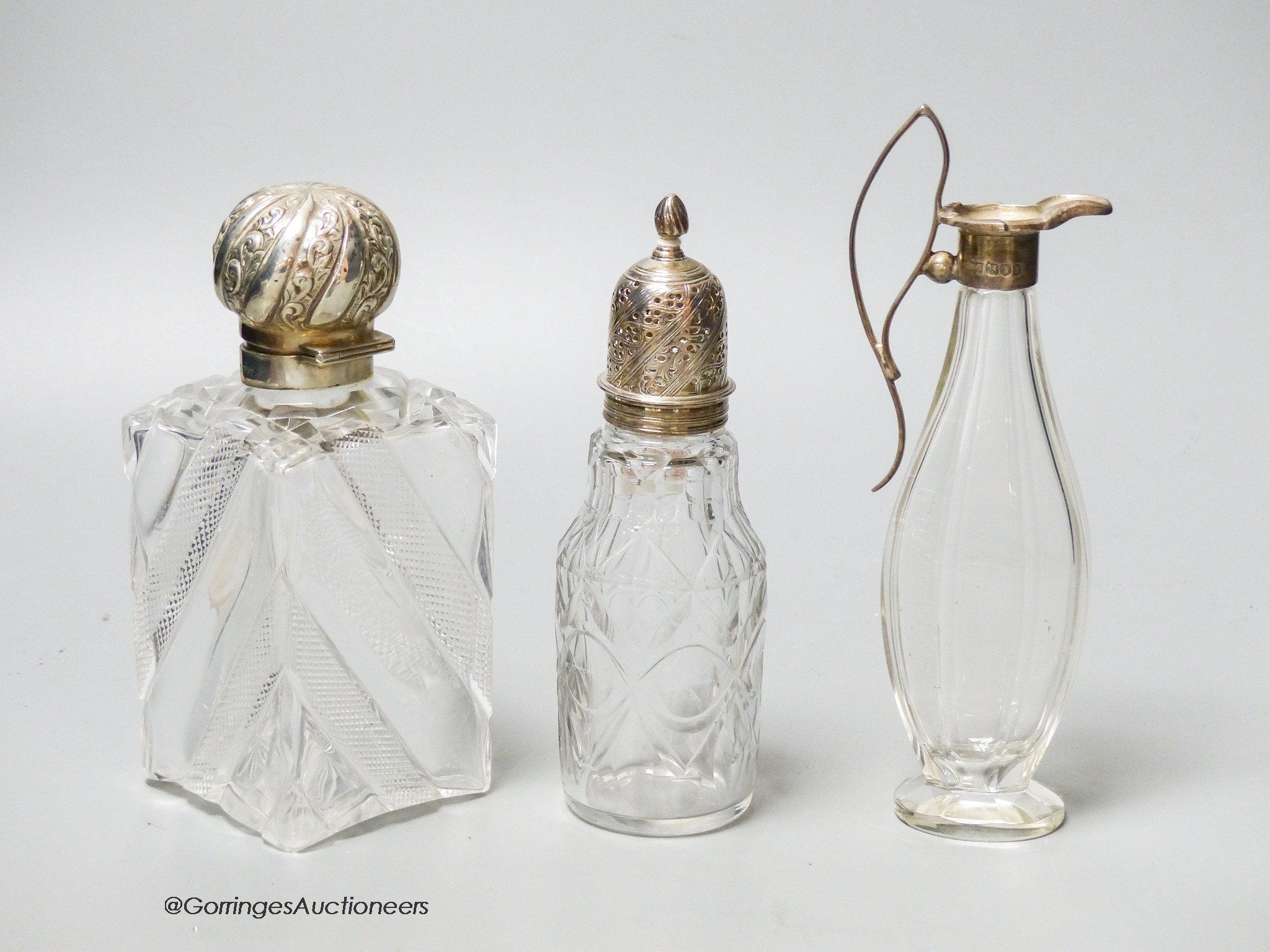 A late Victorian silver topped cut glass scent bottle, London, 1890, 15cm, a later silver mounted glass condiment ewer and silver mounted glass caster.                                                                     