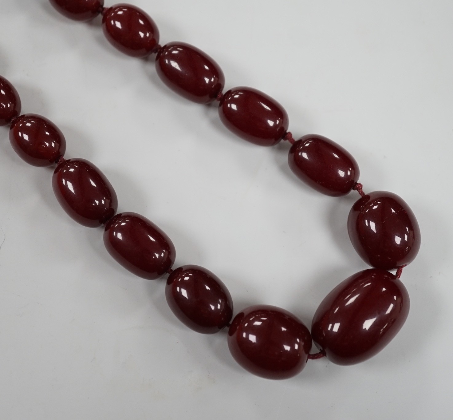 A single strand graduated simulated cherry amber necklace, 82cm, gross weight 83 grams.                                                                                                                                     