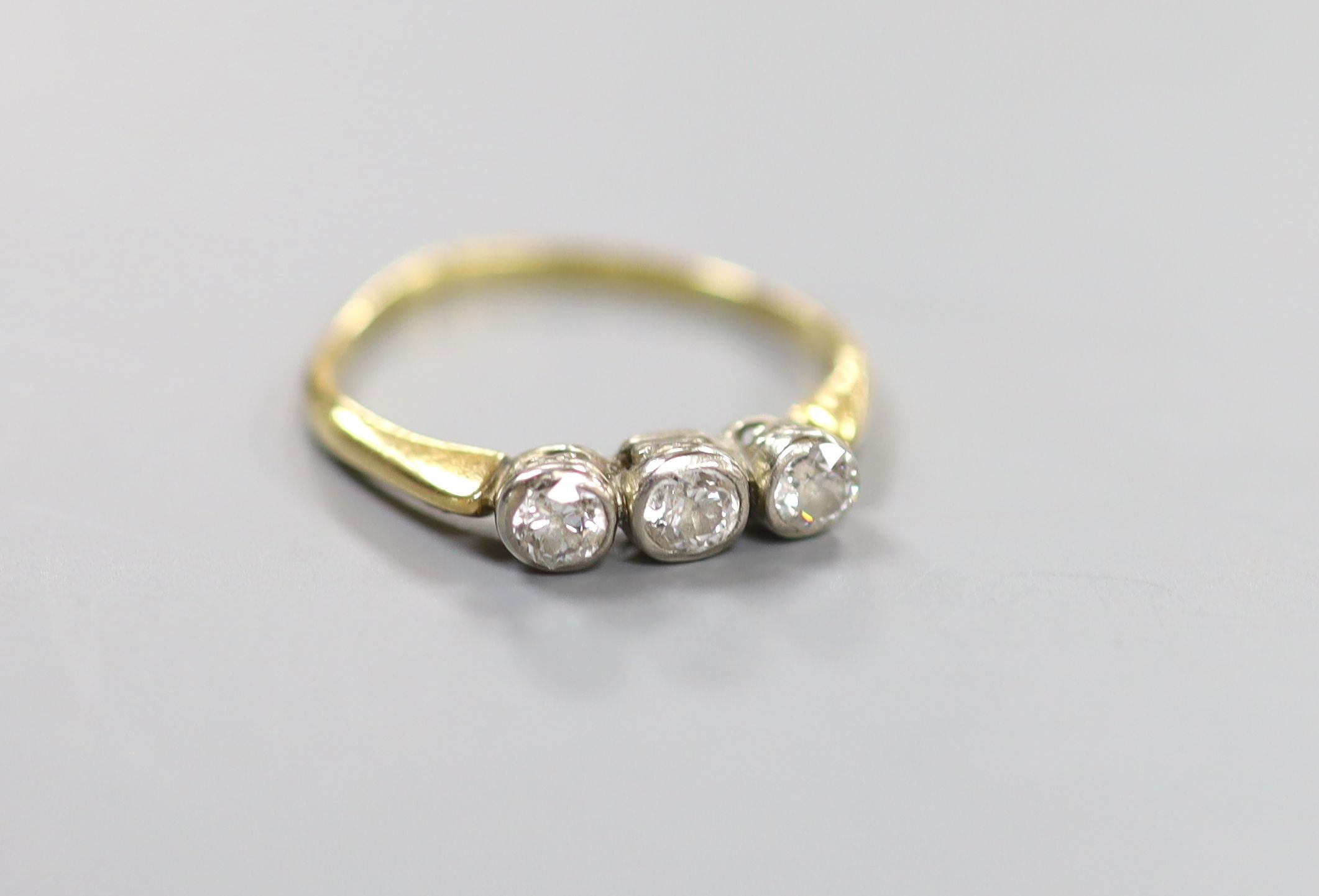 An 18ct and collet set three stone diamond ring, size R, gross weight 2.6 grams.                                                                                                                                            