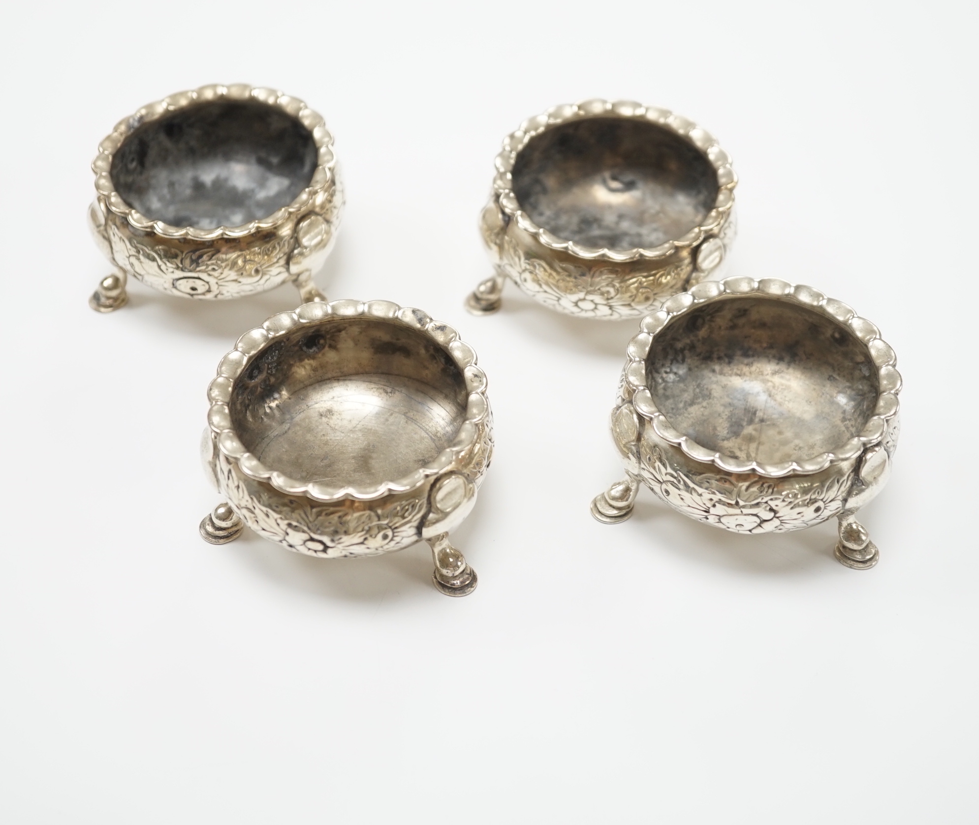 A set of four George II silver bun salts, William Gilchrist, Edinburgh, 1755?, diameter 64mm, 11.1oz, with later? embossed decoration.                                                                                      
